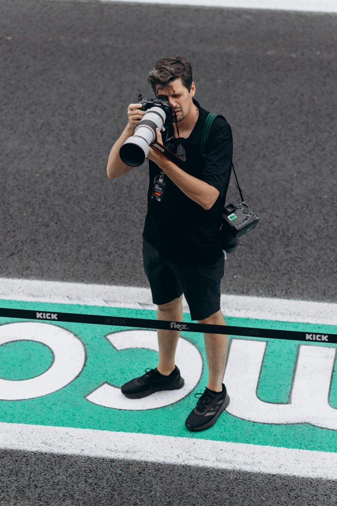 Tournaments Photographer capturing moments at a racing event with a telephoto lens.